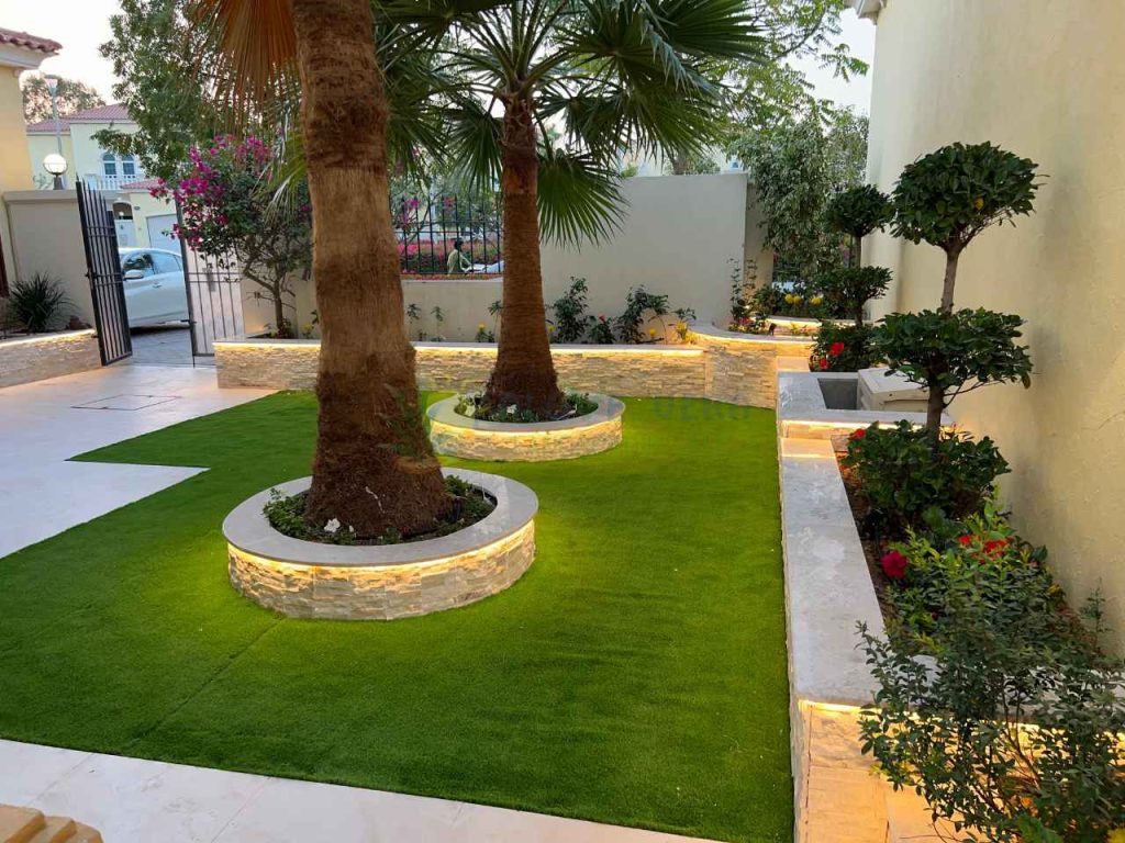 garden lights installed in flower beds and trees covered with artificial grass