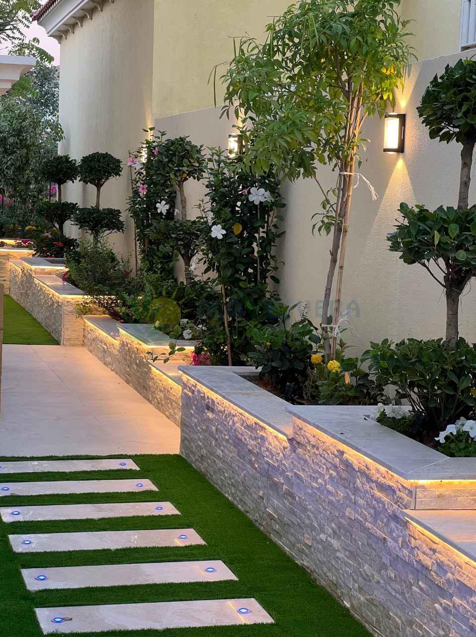 flower beds and paved walkway with garden lights